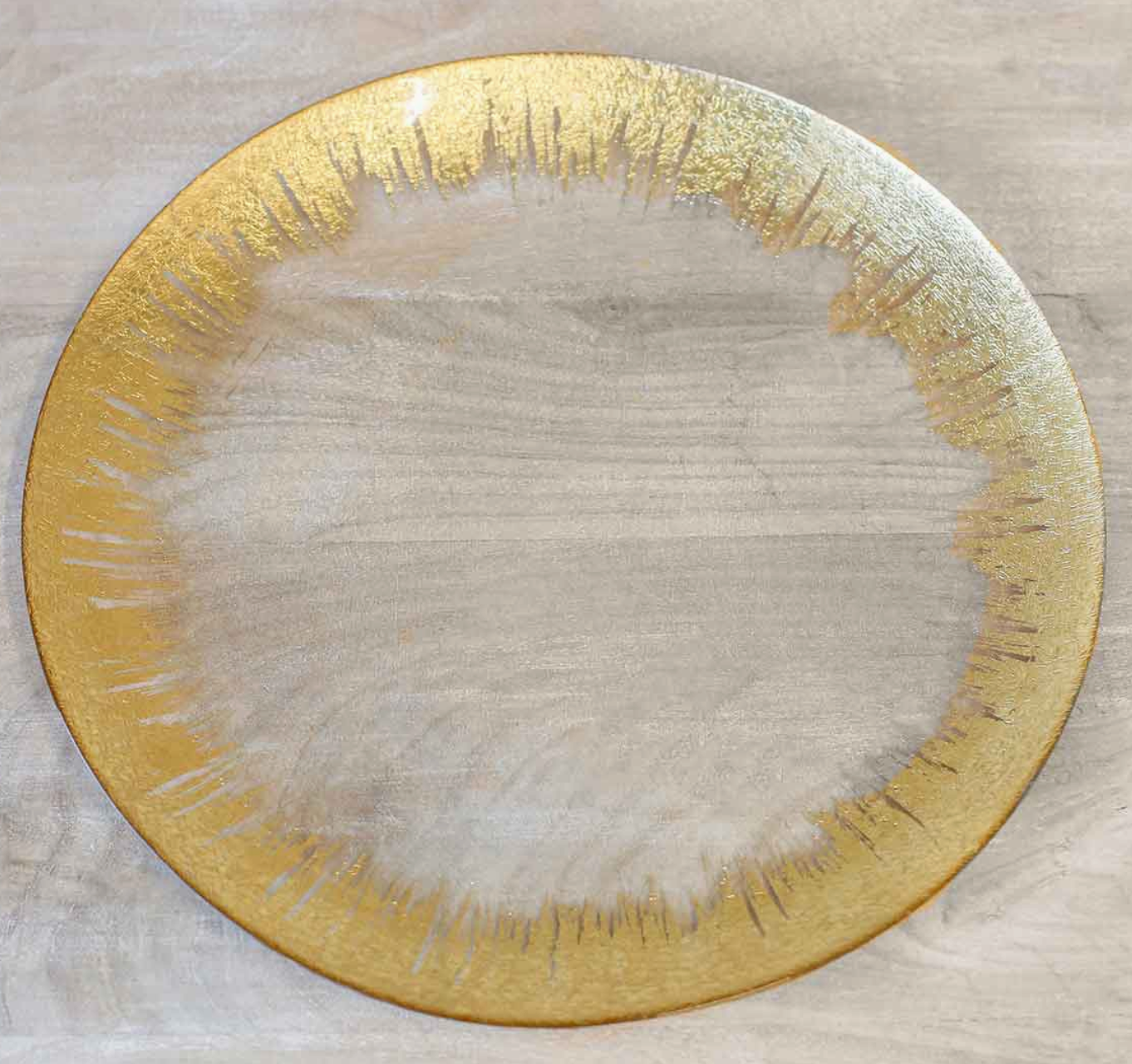 A round glass platter with a gold-colored rim and a textured center.